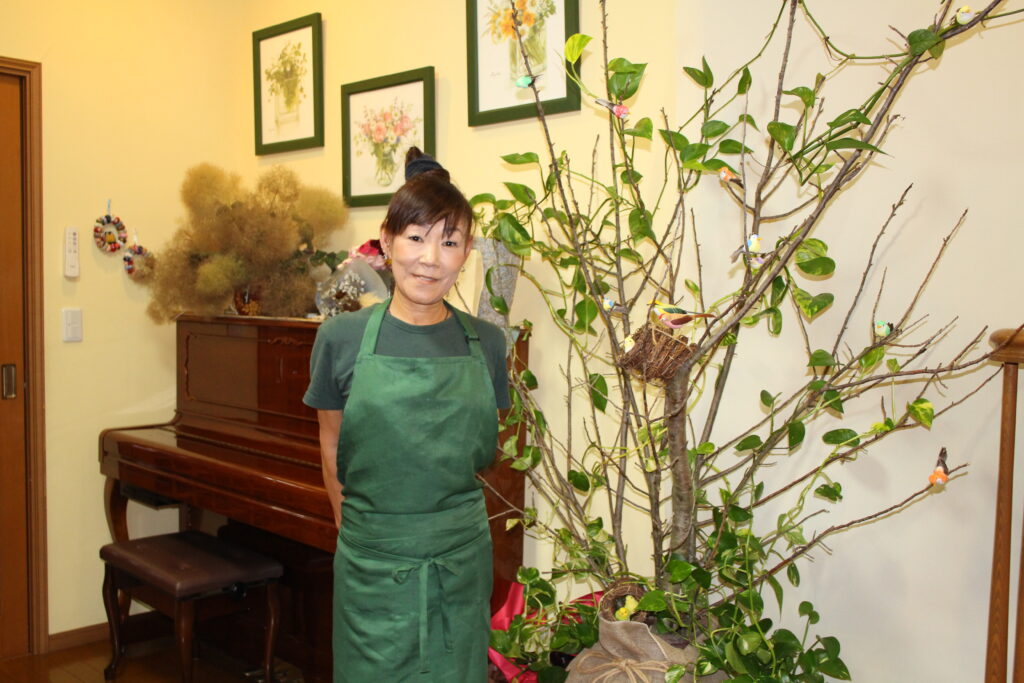 店主の金澤敦子さん。桜の木を生かしたオブジェは金澤さんの手作り
