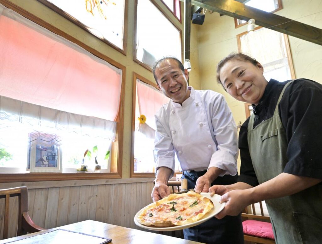 専用の窯で焼き上げたピザを提供する「下妻イタリアン　ダ　フィオーレ」の山岸真毅シェフと妻の千恵子さん（左から）＝下妻市下木戸