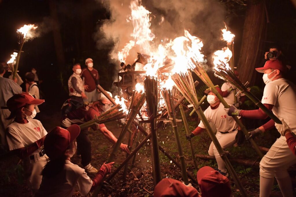 たいまつに火を移す、「かったて祭り」の参加者ら=2021年8月31日午後6時半ごろ、桜川市真壁町山尾