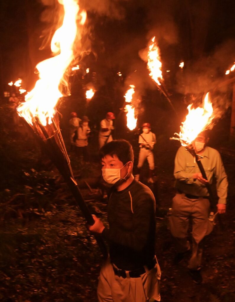 たいまつをかざす「かったて祭り」の参加者＝2022年8月31日、桜川市真壁町山尾の五所駒瀧神社