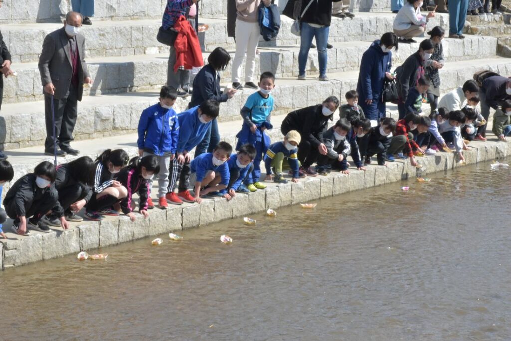 真壁のひなまつりの「和の風流し雛」に参加し、折り紙のひな人形を山口川に流す子どもたち＝2020年3月1日、桜川市真壁町飯塚