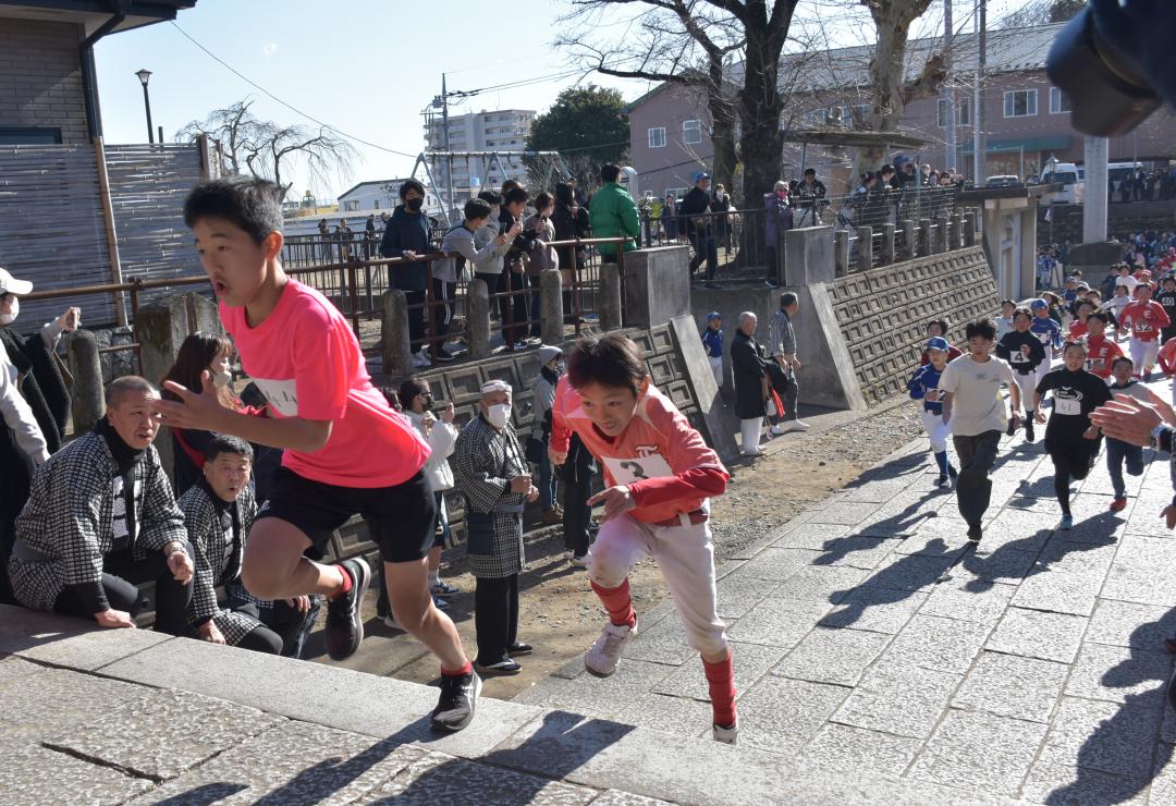 羽黒神社の階段を駆け上がる「招福舘男舘女」の参加者ら=2025年1月13日、筑西市甲