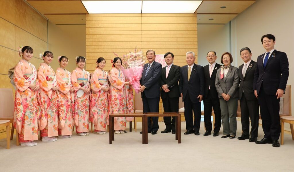 観光大使「古河桃むすめ」から桃の花を受け取る石破茂首相（中央）＝2025年2月20日、首相官邸（永岡桂子衆議院議員事務所提供）