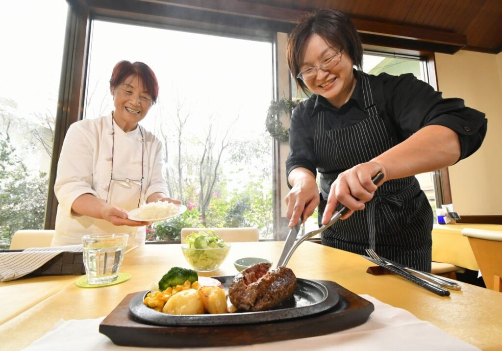 俵ハンバーグを提供する「ペンギン」。店主の井上のり江さん(左)と女性スタッフが笑顔で接客する=桜川市真壁町塙世