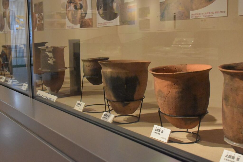 発掘時のパネル写真と一緒に展示される土師器