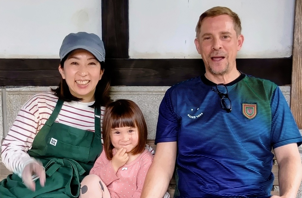 クリスさん(右)と妻の奈々絵さん、真ん中は娘さん