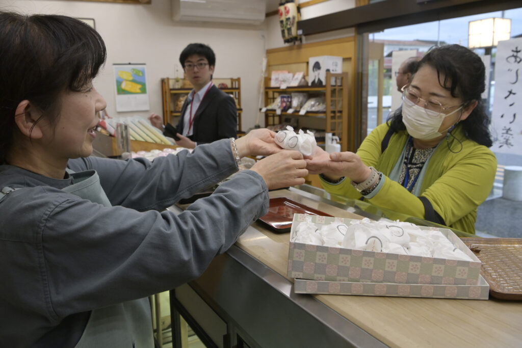 藤井名人のおやつに選ばれたお菓子を買い求めるファン（右）＝5月30日、古河市横山町