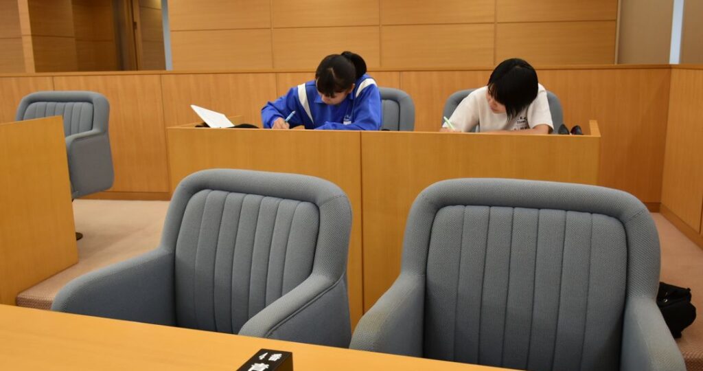 開放された境町議会の議場で、議員席に座って勉強する中学生ら=2019年7月