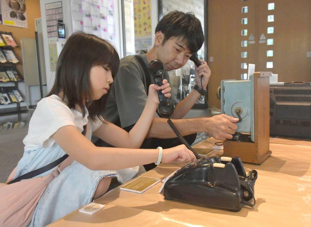 体験コーナーで昭和時代の電話に触れる来館者=下妻市長塚乙