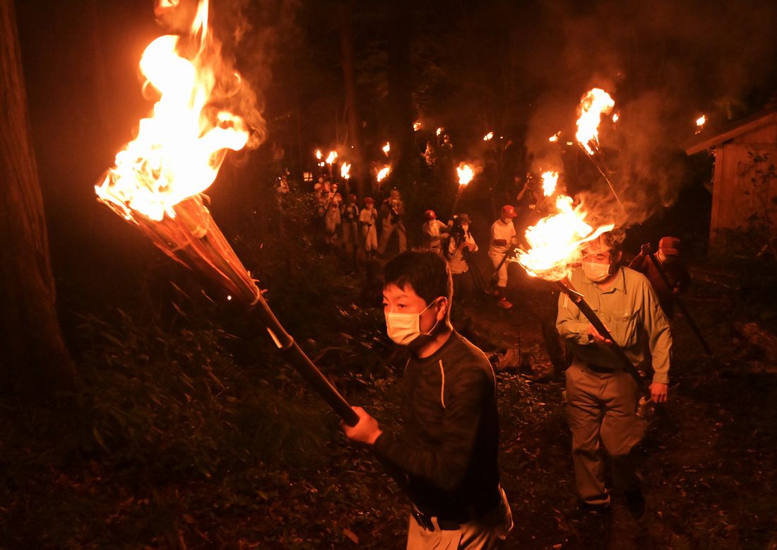 たいまつをかざして権現山の入り口に向かう「かったて祭り」の参加者＝2022年8月31日午後6時39分、桜川市真壁町山尾の五所駒瀧神社