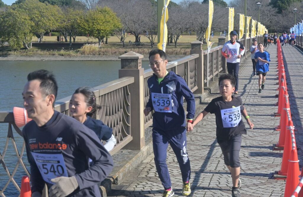 親子で並走して懸命に走る参加者たち=2023年11月19日、下妻市の砂沼大橋
