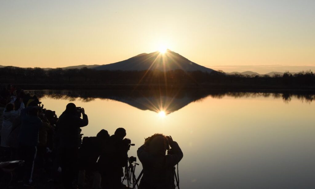 筑波山頂に現れた朝日「ダイヤモンド筑波」と、母子島遊水地に集まったカメラマンら=2019年2月14日午前6時55分ごろ、筑西市飯田