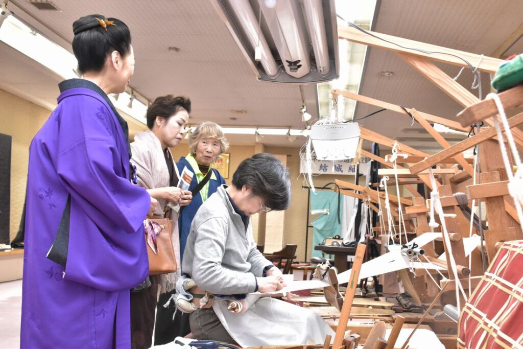 結城紬の機織りの様子に見入る参加者=2019年11月9日、結城市結城