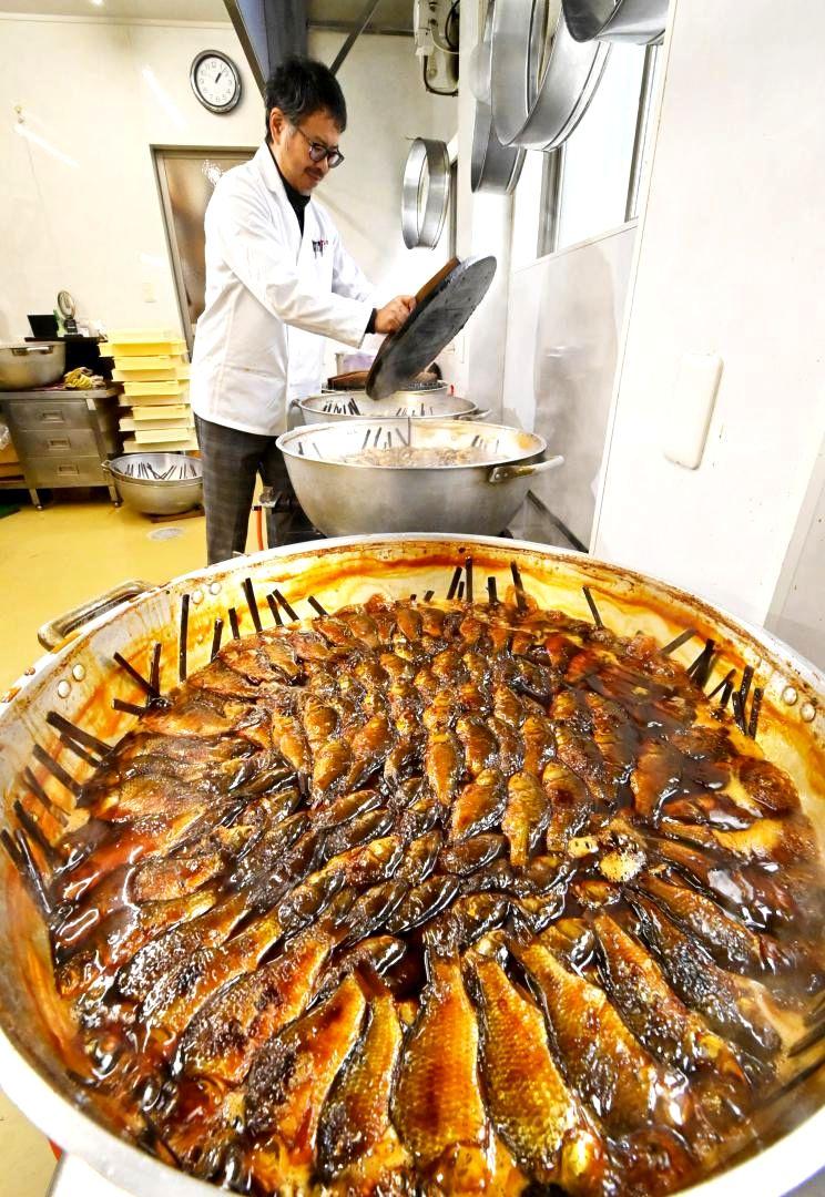 最盛期を迎えたフナの甘露煮作り。大鍋に並べられたフナは長時間煮込まれ、あめ色になりました=古河市本町