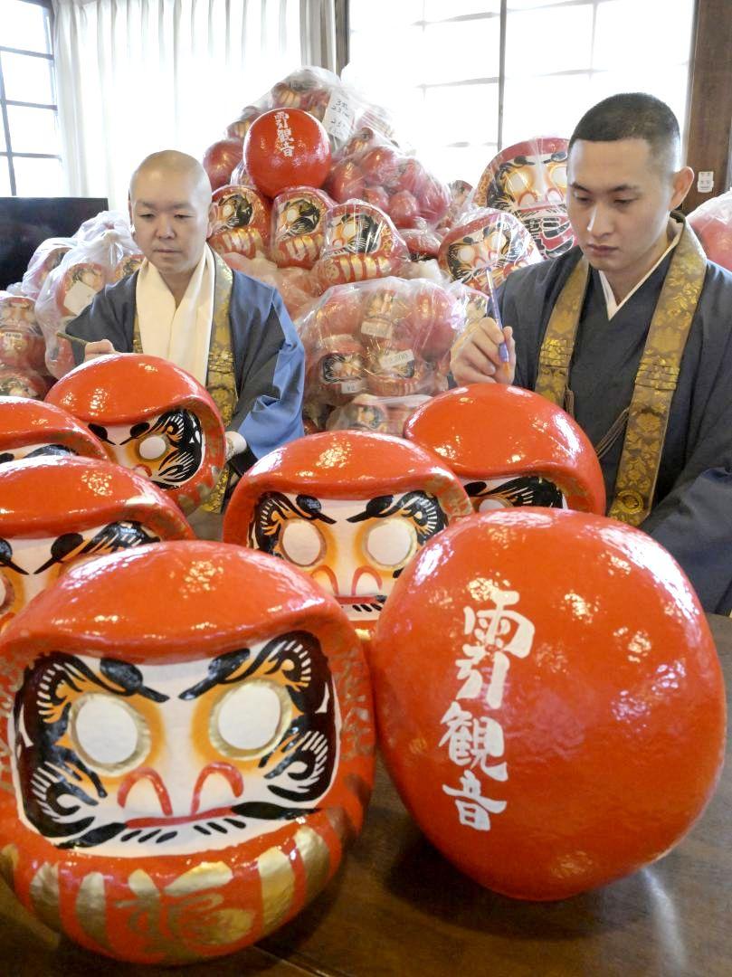 「福だるま」の背に筆を入れる僧侶ら=桜川市本木の雨引山楽法寺