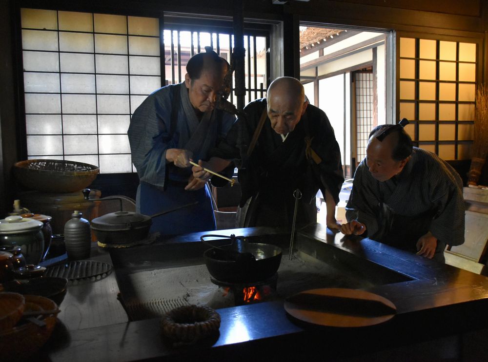 鷹見泉石(中央)や奉公人がカステラを焼くシーン=鷹見泉石記念館