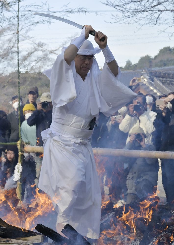 刀を振るいながら火の道を歩く先達＝2024年12月21日午後、桜川市真壁町長岡