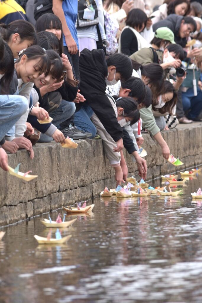 折りびなを山口川に流す参加者ら＝2025年3月2日、桜川市真壁町飯塚