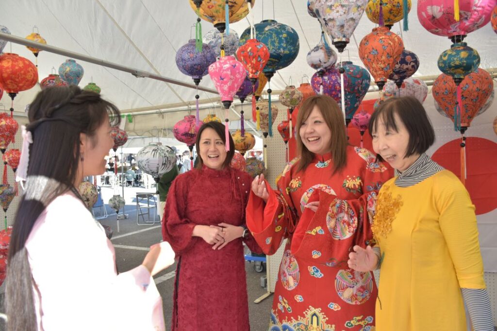 「八千代の秋まつり」でベトナム伝統衣装を試着する女性ら=2025年11月22日、町総合体育館周辺