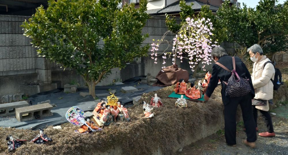 庭に展示されたひな人形を見る女性ら