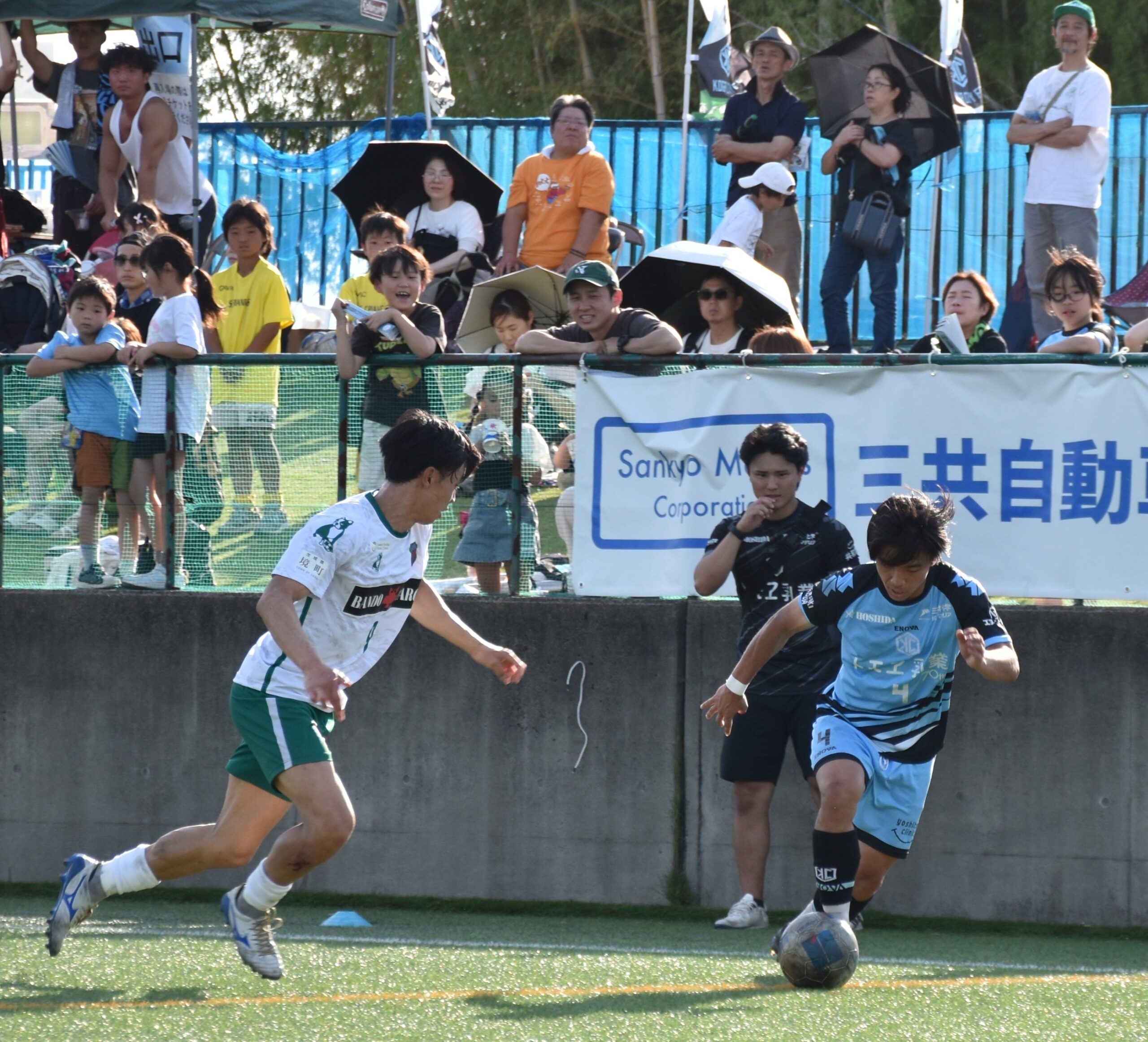 地元の声援を受けながらプレーする古河シティFCと境トリニタスの選手たち=古河市駒ケ崎