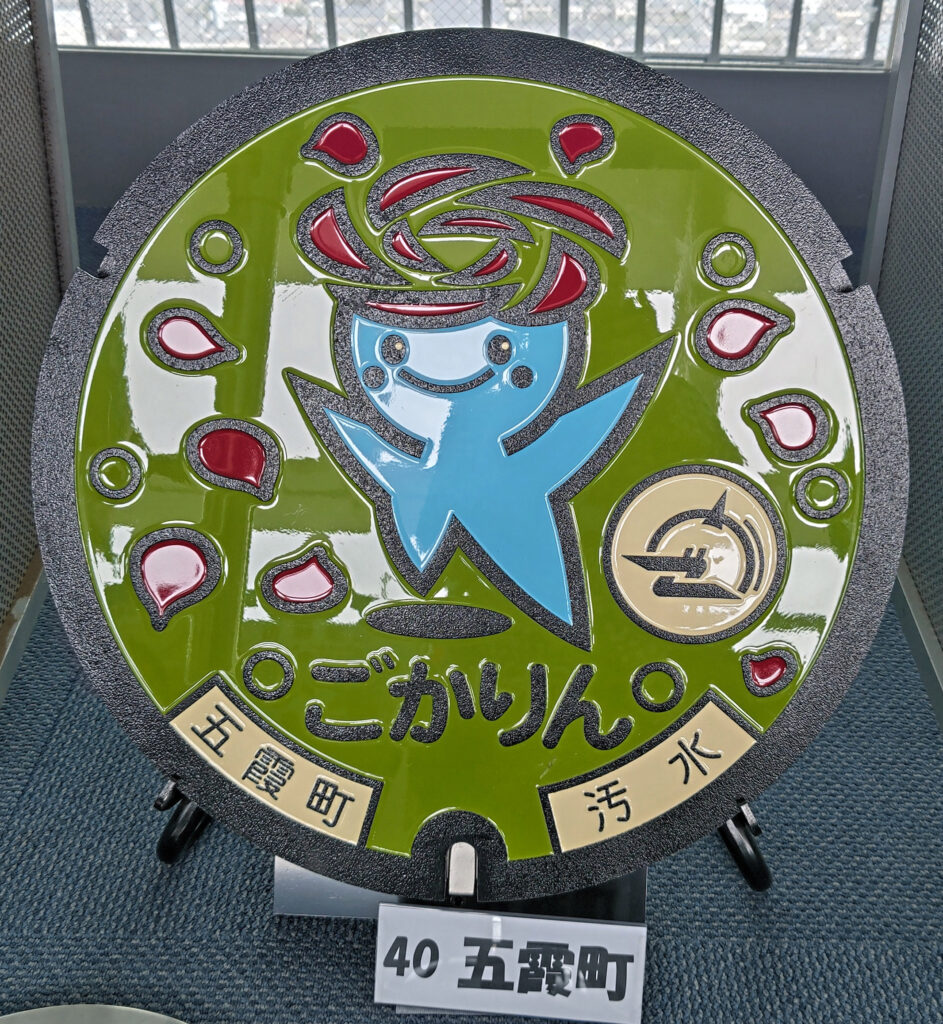 市の公式キャラクター「ごかりん」とバラの花びらをあしらった五霞町のマンホール=水戸市笠原町
